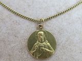 a close up of a gold plated necklace with an image of the virgin and child