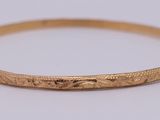 a close up of a gold bang bracelet with engraving on it