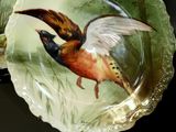 a plate with a bird painted on it next to a bowl