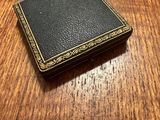 an old black book sitting on top of a wooden table