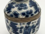 un vase bleu et blanc muni d'un couvercle, posé sur une surface blanche