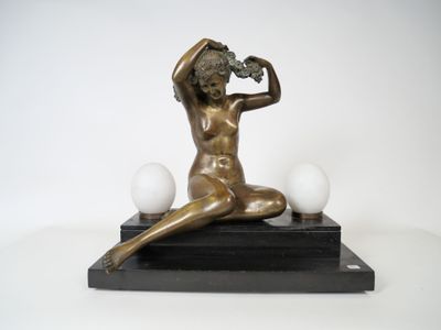 bronze statue of a woman sitting on a marble base with three eggs
