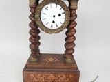 une petite horloge en bois avec un pendule et une paire de ciseaux à côté