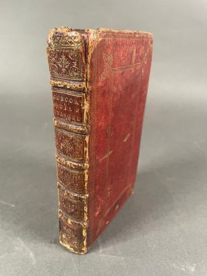 un vieux livre rouge aux tranches dorées posé sur une table