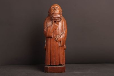 une vieille statue en bois représentant un moine barbu vêtu d'une robe