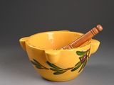 yellow bowl with a mortar and a wooden stick in it