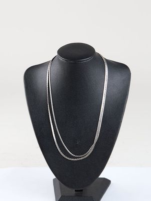 black mannequin with a silver chain on a black stand