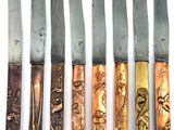six different types of knives are lined up on a white surface
