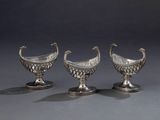trois vases en argent empilés les uns sur les autres, posés sur une table