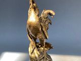 bronze statue of a rooster on a rock with a star in the background