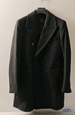 un manteau en laine noir suspendu à un cintre sur un mur blanc