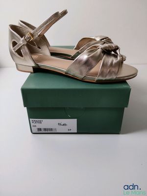 Les chaussures dorées se trouvent sur la boîte verte posée sur la table blanche.