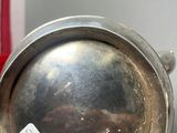 a silver pot sitting on a table next to a red cup