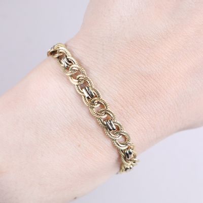 a close up of a person ' s hand wearing a gold chain bracelet
