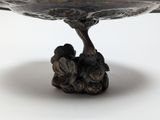 a silver bowl with a bird on it on a table