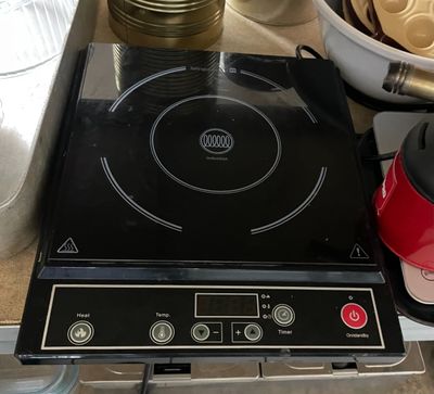 une plaque de cuisson noire surmontée d'un brûleur noir