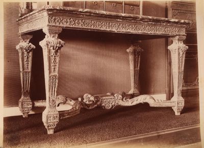 une vieille photo d'une table très ouvragée au milieu d'une pièce