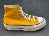 yellow high top converse sneakers with white laces on a black surface