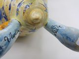 a close up of a blue and yellow vase with a tag on it