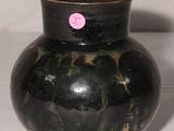 un vase noir sur lequel est collé un autocollant rose