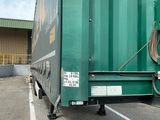 un grand camion-benne vert garé sur un parking