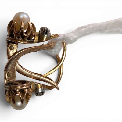 a close up of a brooch with a pearl in it