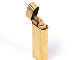 a gold lighter that is sitting on a white surface