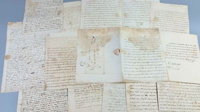 several old manuscripts are stacked on top of each other on a table