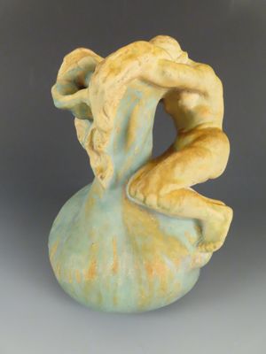 une sculpture en céramique représentant une femme assise sur un vase