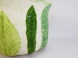 a green and white vase with a leaf design on it