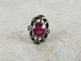 a close up of a ring with a ruby stone in it