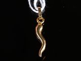 un pendentif en forme de serpent plaqué or, muni d'un cordon blanc, sur fond noir