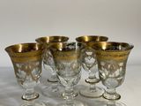 six glasses with gold rims are lined up on a white surface