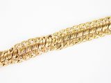 gros plan d'un bracelet en or sur une surface blanche
