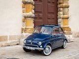 a small blue car parked in front of a brown door