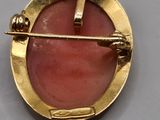 an image of a gold and pink broochle broochle on a gray surface