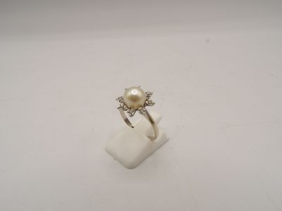 une image d'une bague en perles et diamants sur une surface blanche