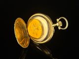 a gold pocket watch sitting on top of a black surface