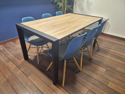 a wooden table with blue chairs and a potted plant in the corner