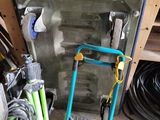 a small blue cart with a green handle next to a pile of tools