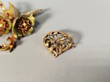a gold brooch and a brooch on a white surface