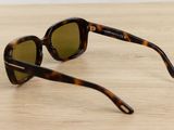 sunglasses on a wooden table with a white wall in the background