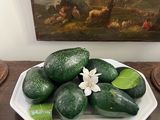 a plate of cucumbers on a table with a painting in the background
