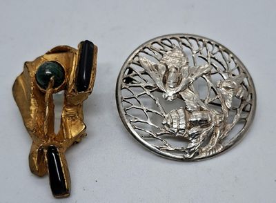 une broche en argent et une broche en or sur un fond blanc