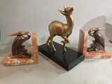 three statues of a deer and a bird on a marble base