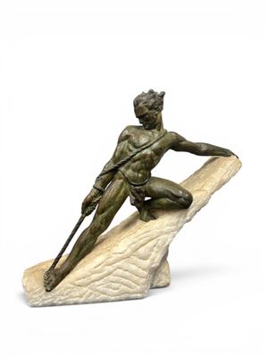 statue d'un homme assis sur un rocher, tenant une lance