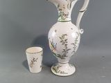 a white vase and a cup sitting on a table