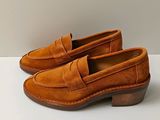 un gros plan sur une paire de chaussures marron posées sur une surface blanche
