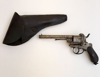 un vieux pistolet dans un étui en cuir posé sur une surface blanche