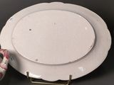 a white plate with a pink flower on it next to a roll of toilet paper